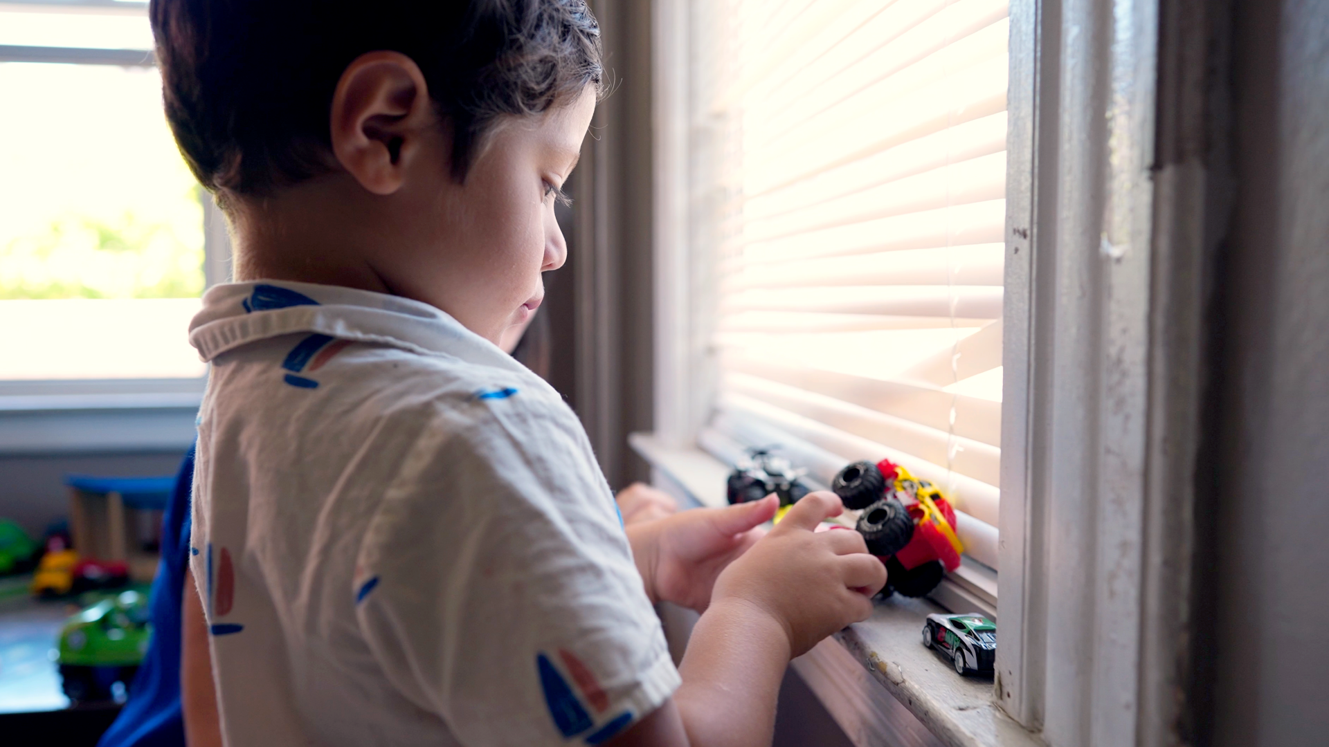 child playing with toy cars on windowsill